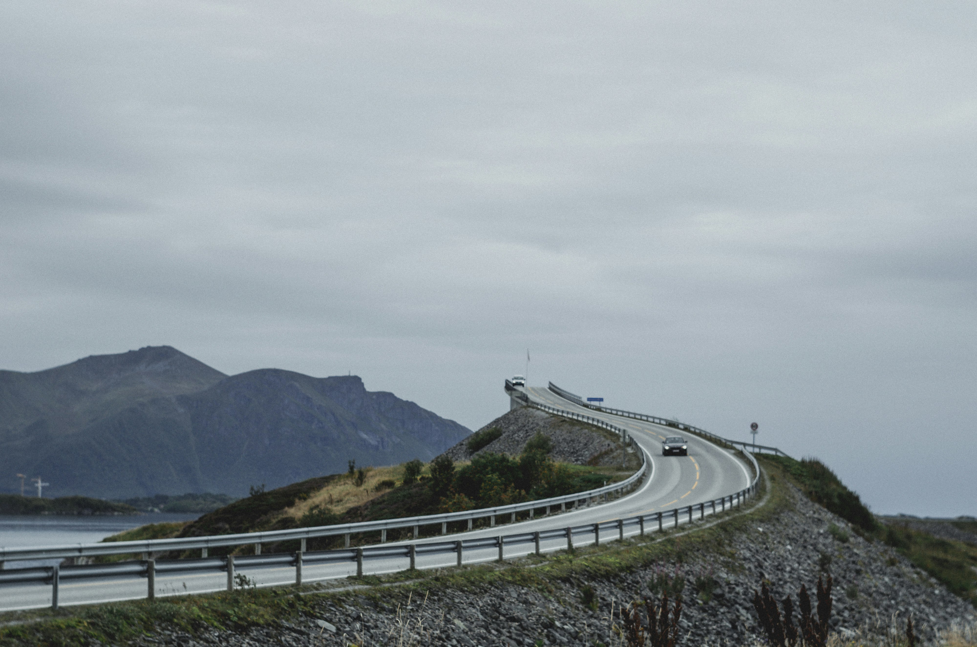 gray concrete road near green mountains during daytime